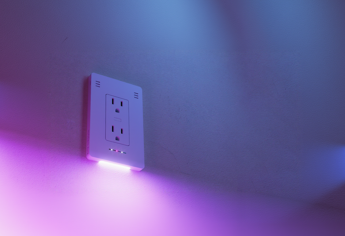 InvisOutlet Aura casting pink and violet light onto a textured wall